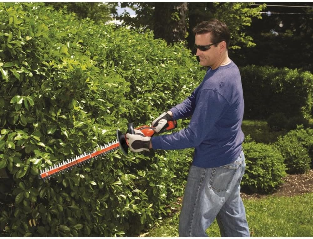 Man using BLACK+DECKER 40V MAX Cordless Hedge Trimmer to trim a hedge