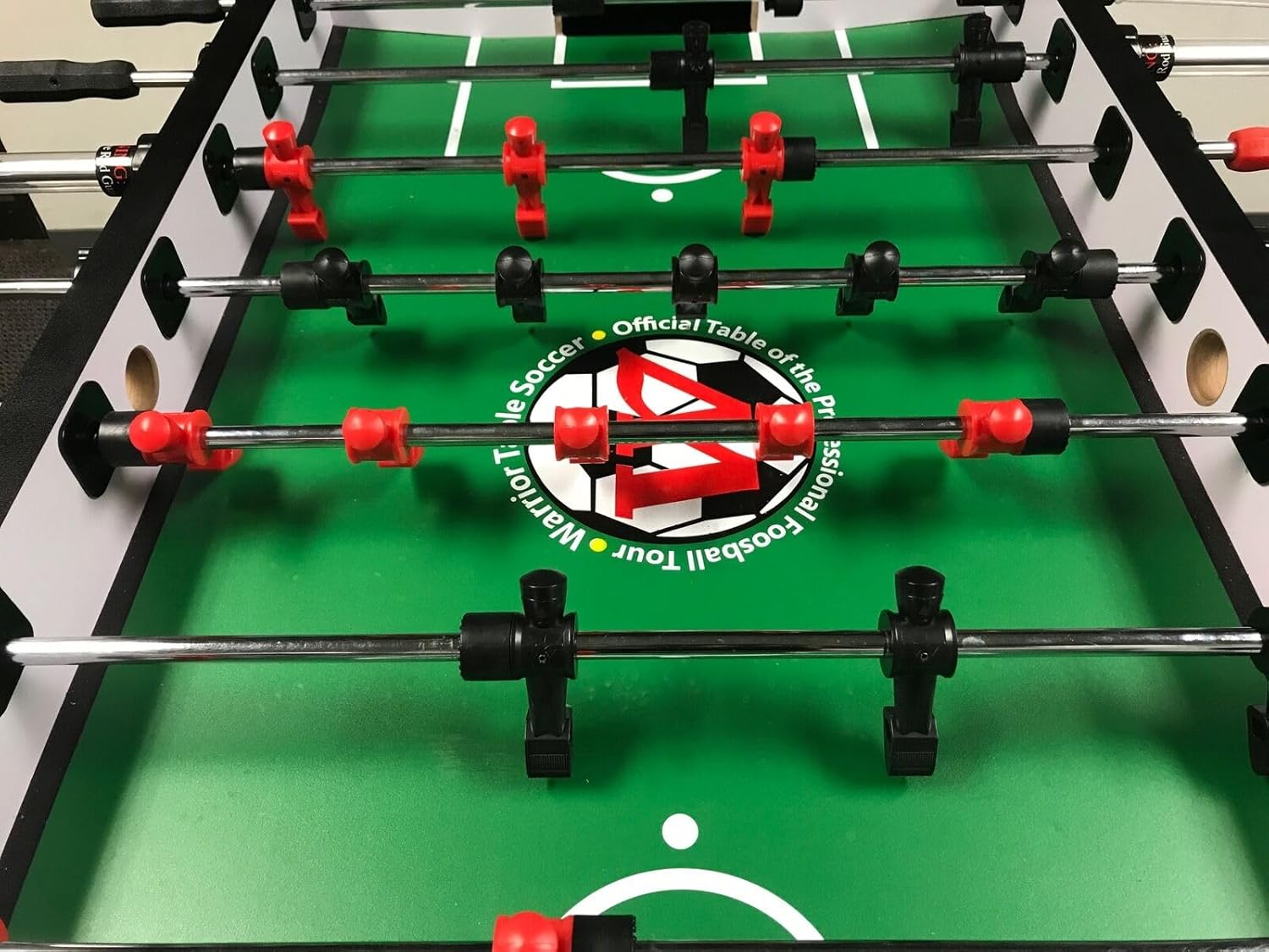 Close-up view of the foosball table playing surface with red and black players, showing the 'Official Table of the Professional Foosball Tour' logo.
