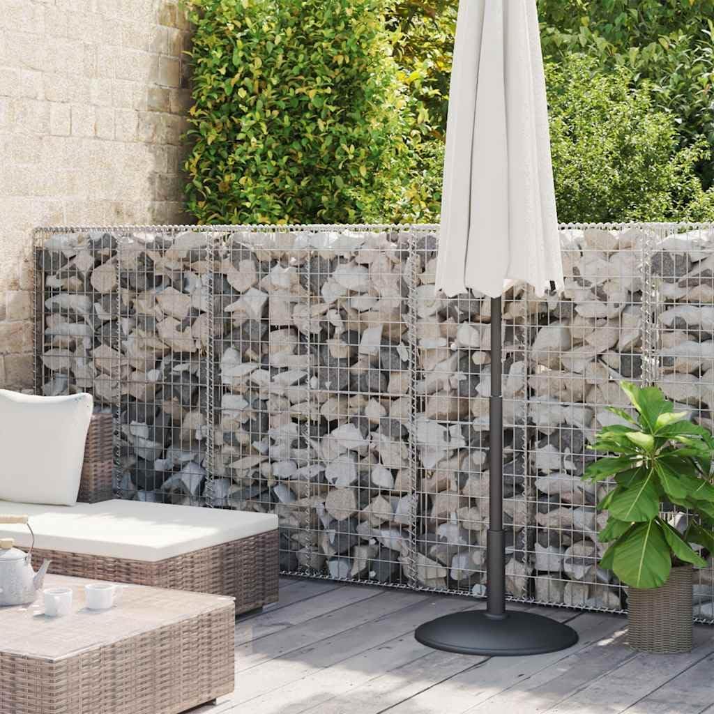A completed gabion wall filled with light-colored stones, serving as a privacy screen or decorative element on a patio.