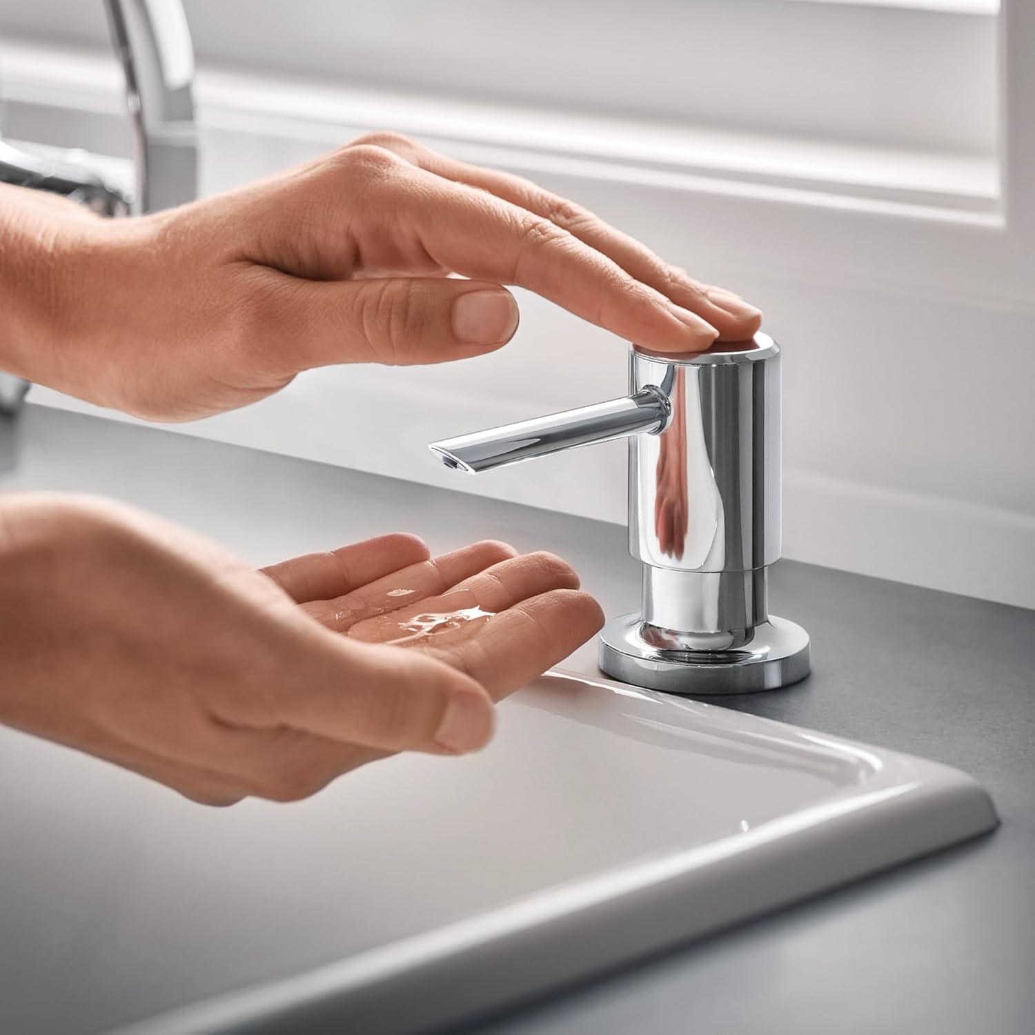 Close-up of a hand pressing the Moen soap dispenser to dispense soap into another hand.