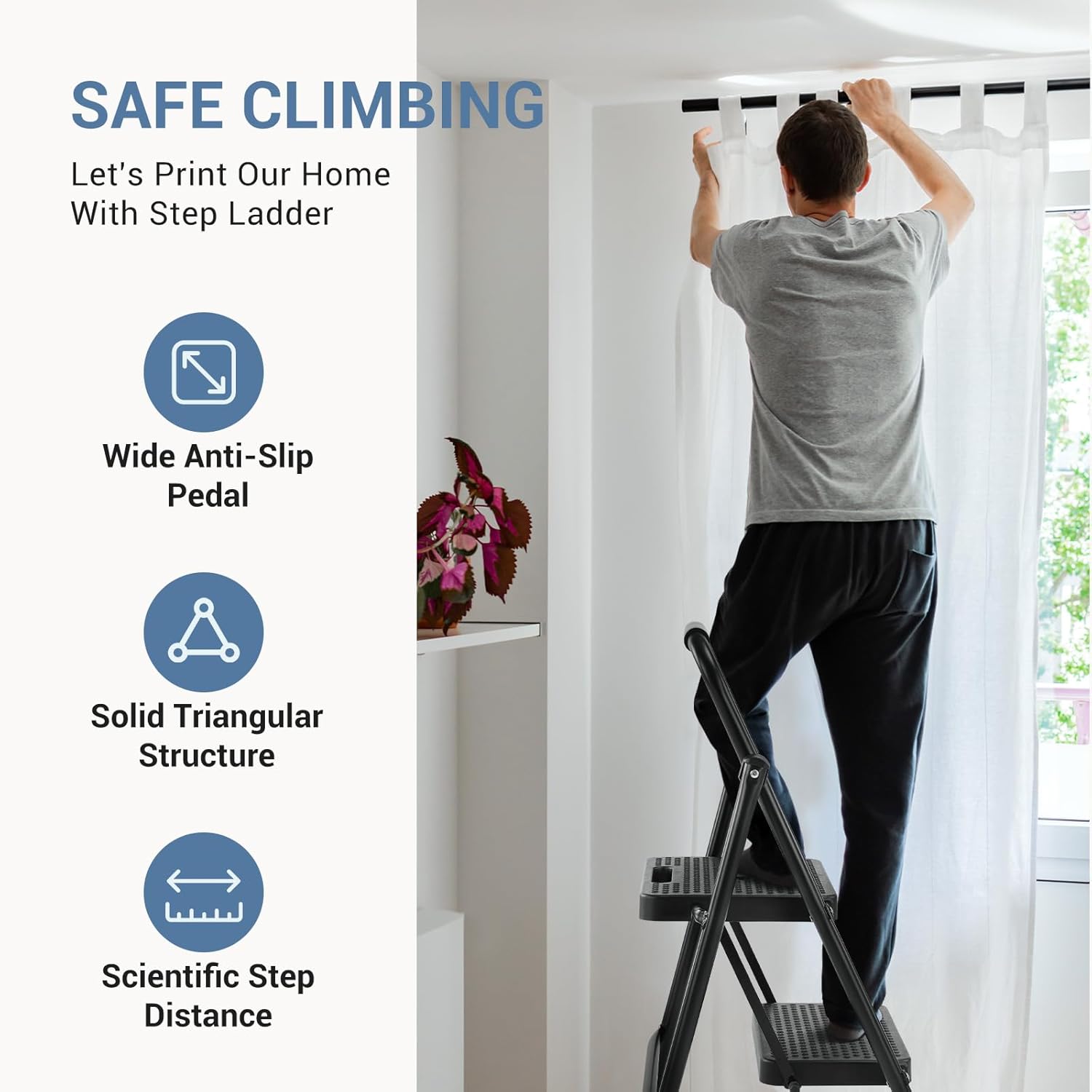 Person standing on the DUMOS 2-step ladder to hang a picture on a wall.