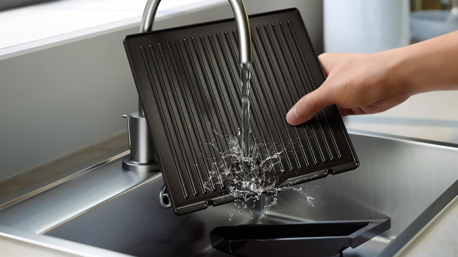 Hand washing a removable grill plate under running water