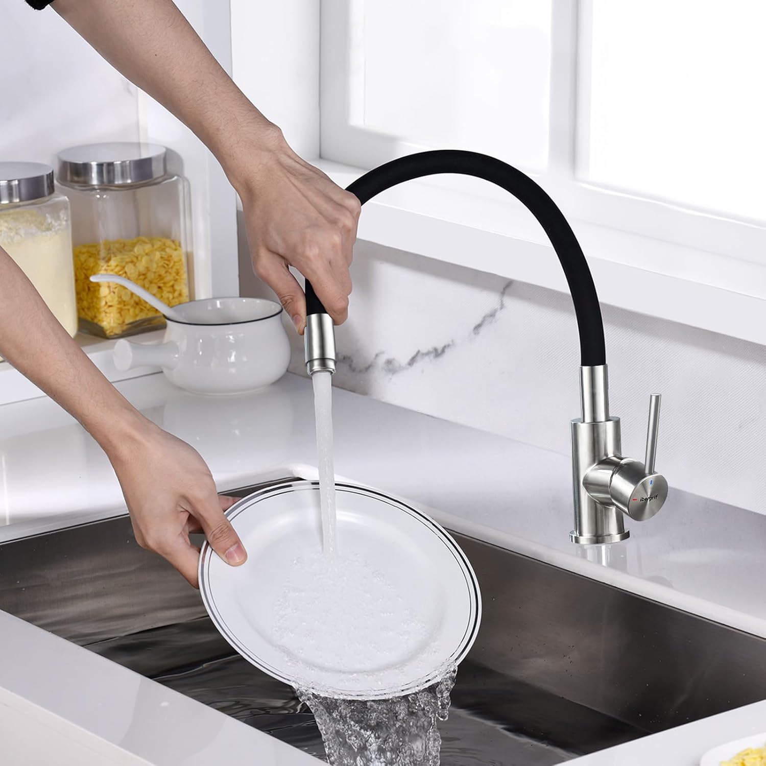 A person using the flexible kitchen faucet to rinse a plate in a sink, demonstrating its practical use.