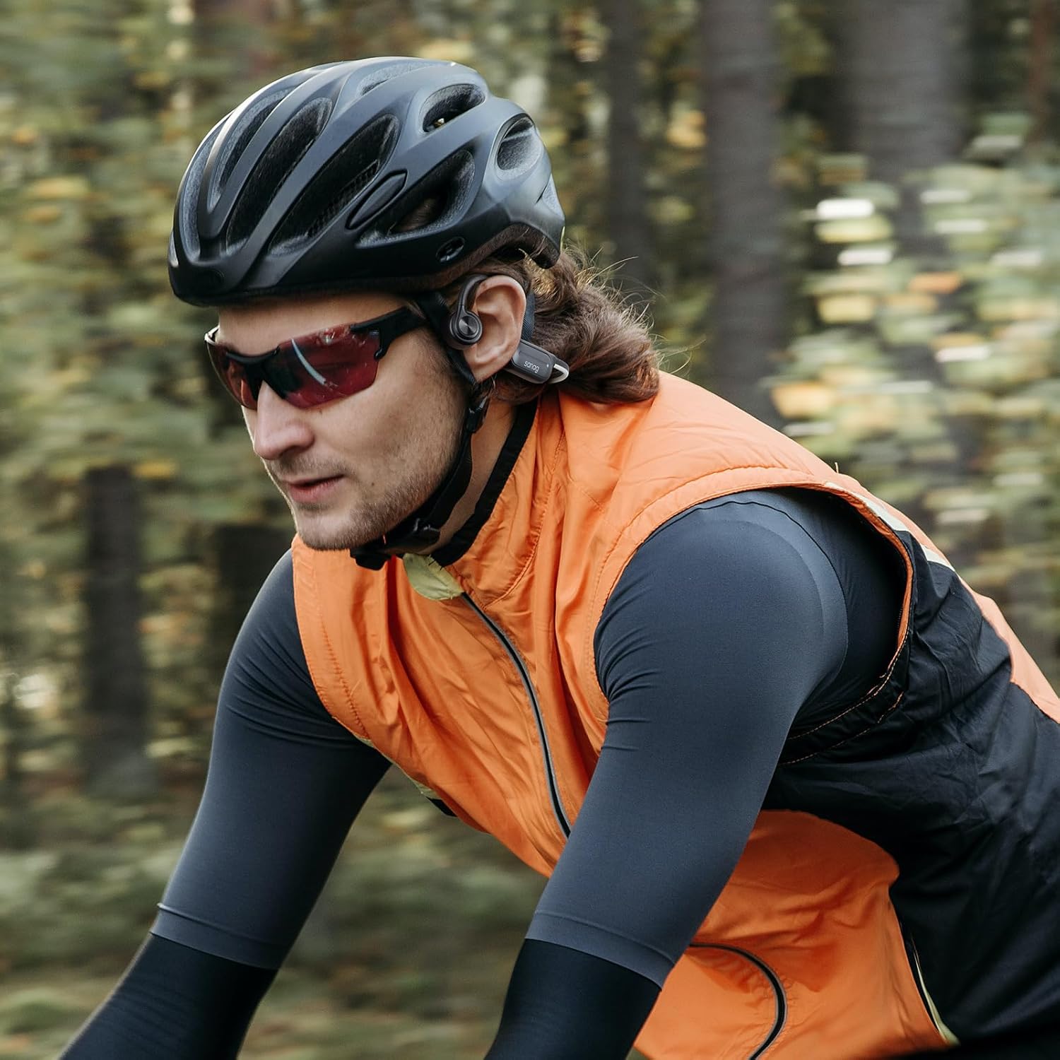 Una persona che indossa le cuffie a conduzione ossea Sanag mentre va in bicicletta, mostra il corretto posizionamento dei trasduttori sugli zigomi.