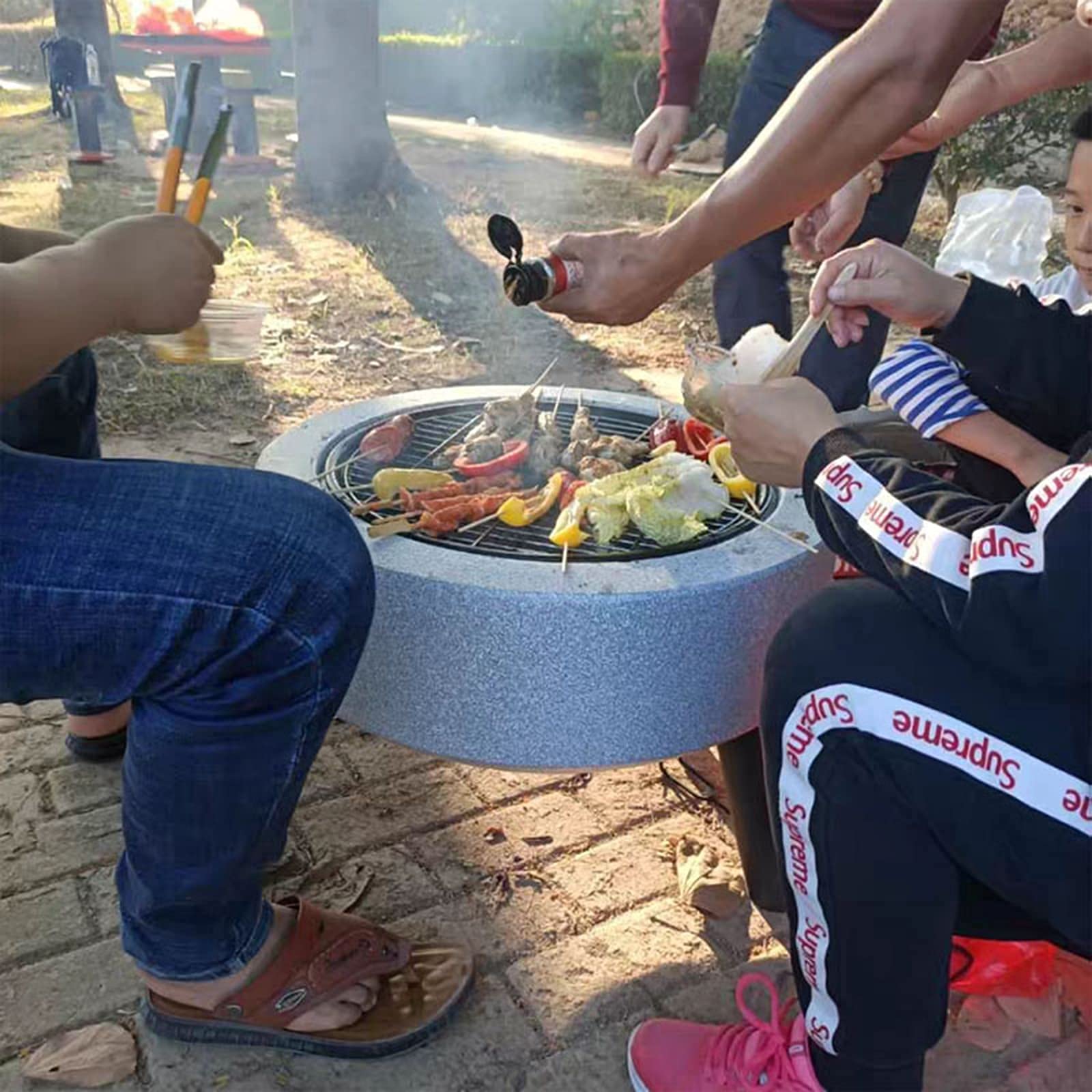 Palenisko ogrodowe z drewna opałowego z okrągłą kratką chroniącą przed iskrami, pogrzebaczem i metalowym grillem.