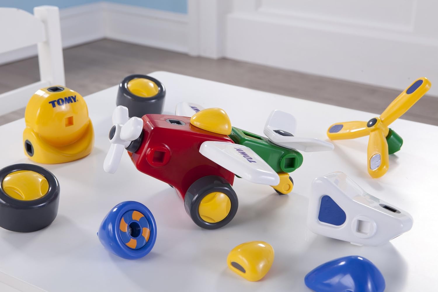 Various Constructables pieces on a table, with a partially assembled red and green airplane.