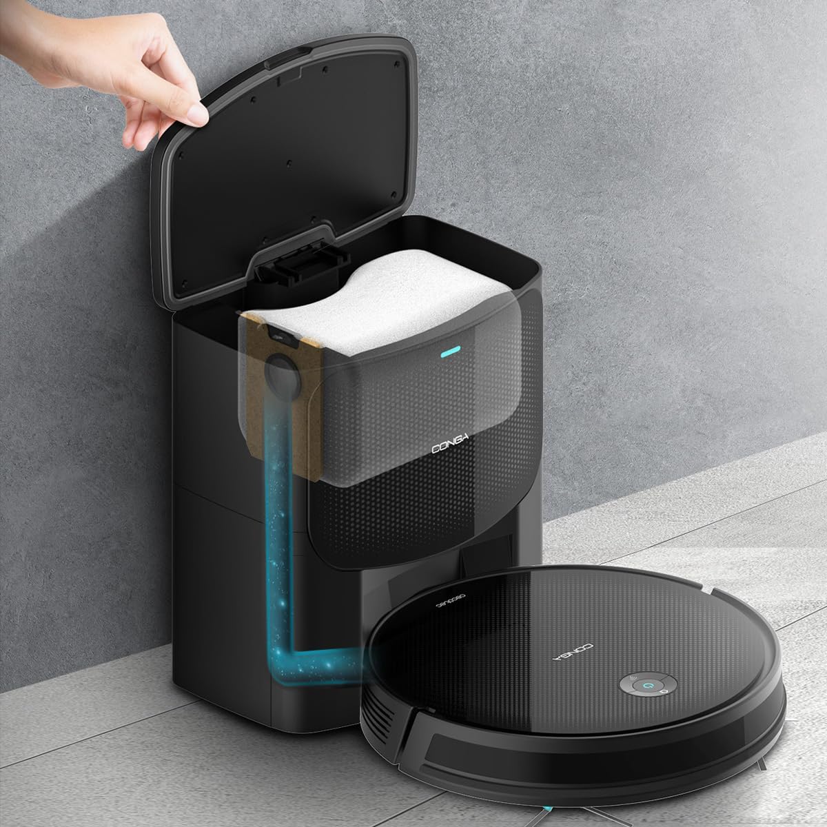 Robot vacuum cleaner docked at its auto-emptying base, with a hand opening the base to show the dust bag