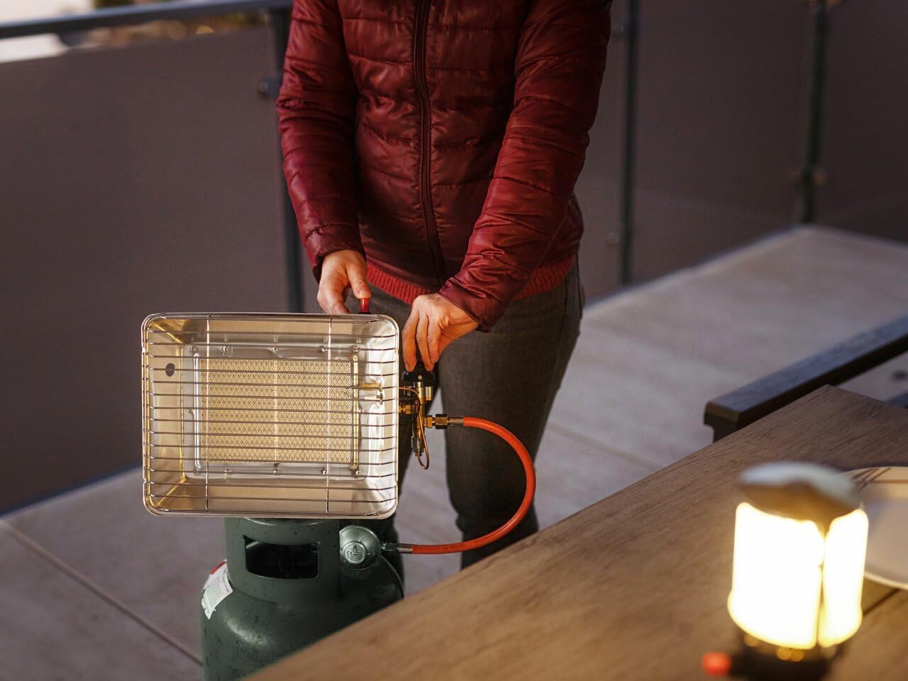 A person's hands adjusting the control knob and pressing the piezo ignition button on the Rothenberger Industrial Gas Radiant Heater.