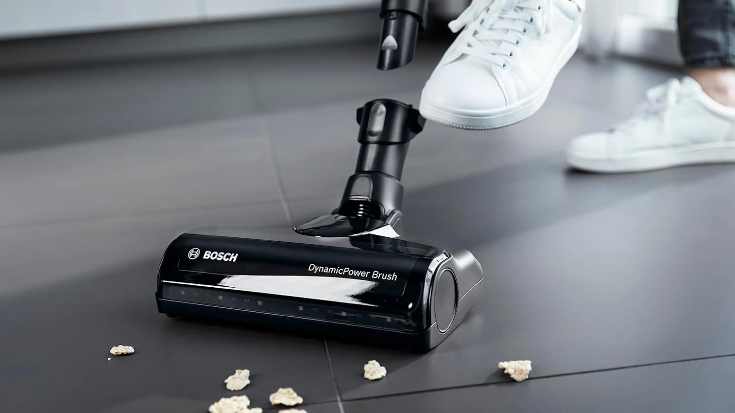Close-up of the DynamicPower Brush floor nozzle with LED lights illuminating debris on a hard floor.