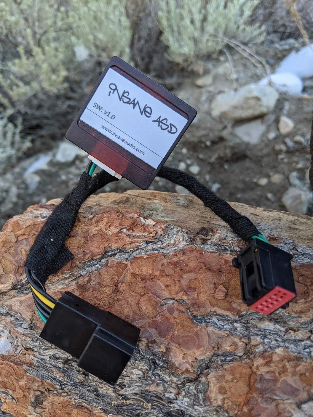 Insane Audio INSANEASD module with wiring, on a piece of wood with bark.