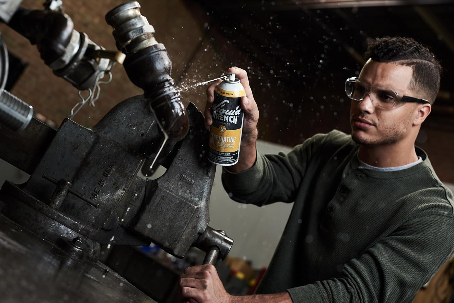 Person spraying Liquid Wrench Penetrating Oil on a rusted bolt in a vise