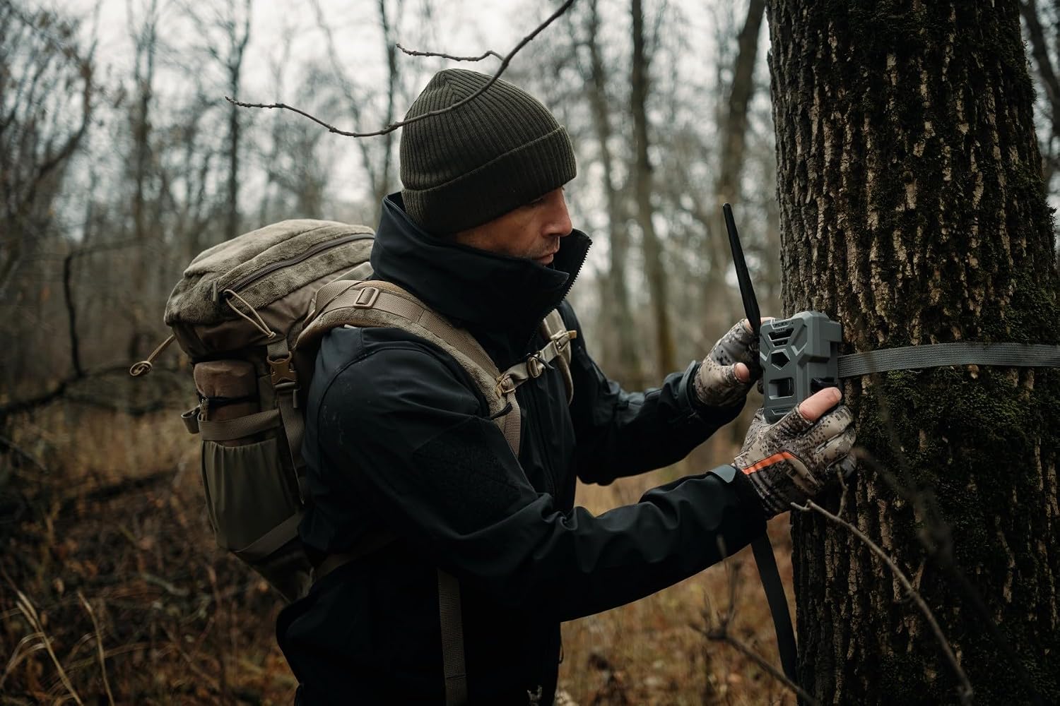 Close-up of a person adjusting a SPYPOINT Flex Dark camera on a tree
