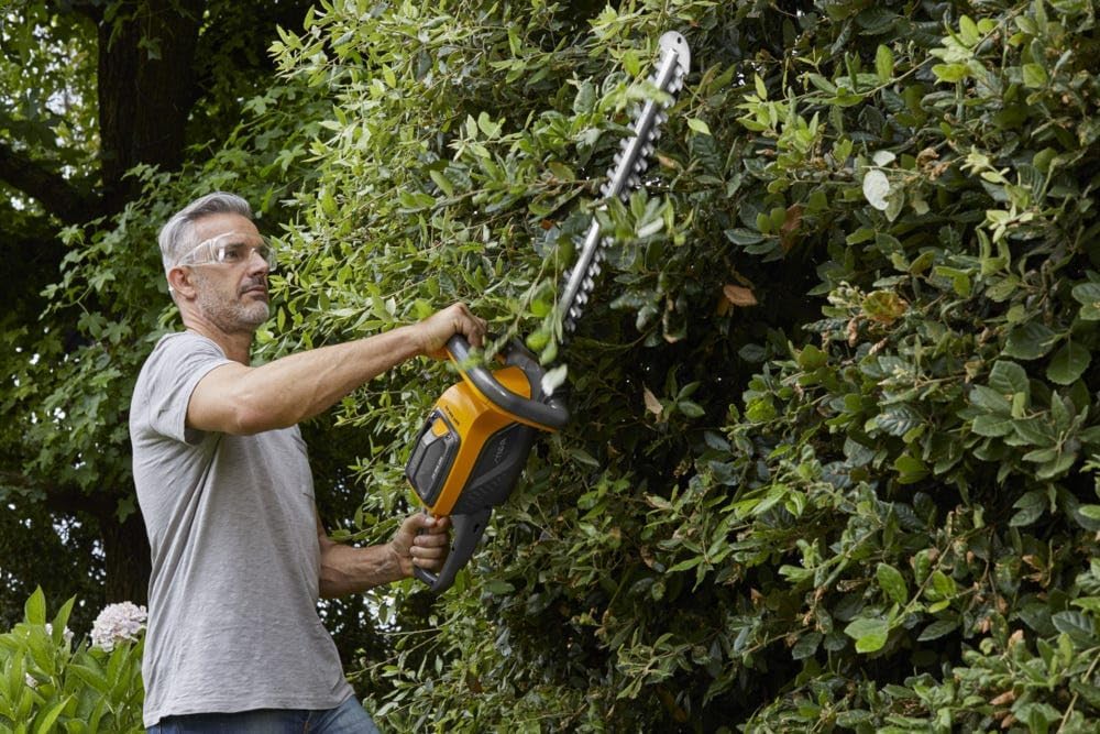 Man using STIGA SHT 500 AE to trim a hedge vertically