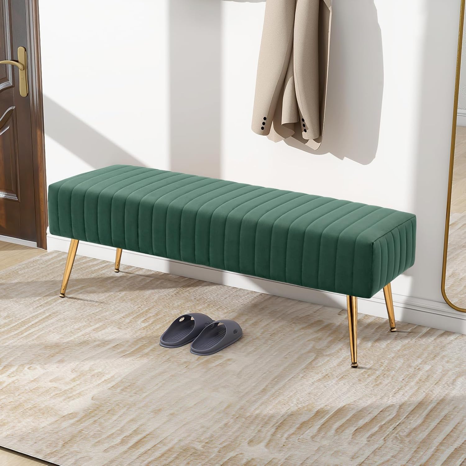 Furniliving entryway bench in a dark green velvet with gold legs, placed in a modern entryway with a coat rack and slippers.