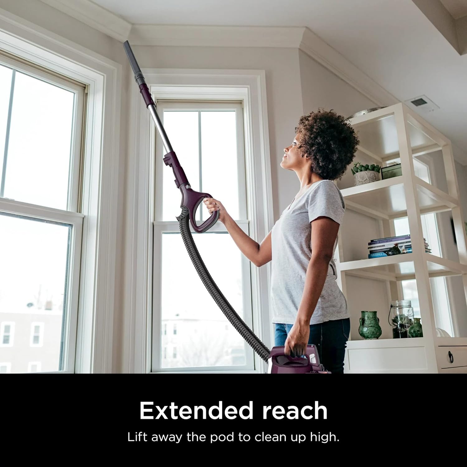 Woman using Shark CU530 in Lift-Away mode with extension wand to clean high areas.