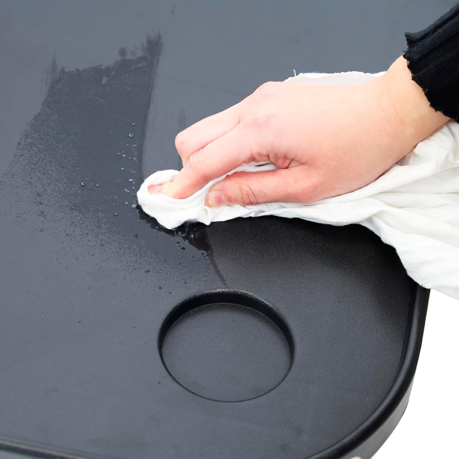 A hand wiping the surface of the wheelchair tray with a white cloth.