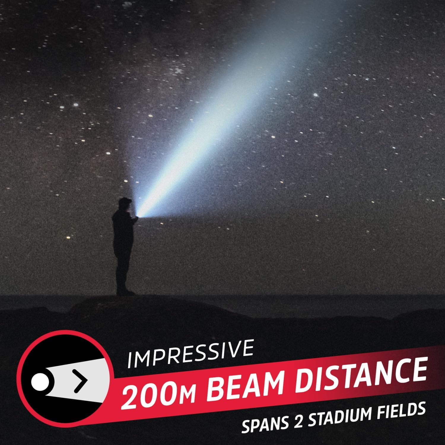 A person standing on a hill at night, illuminating the sky with the Energizer TAC500 flashlight, showcasing its 200-meter beam distance.