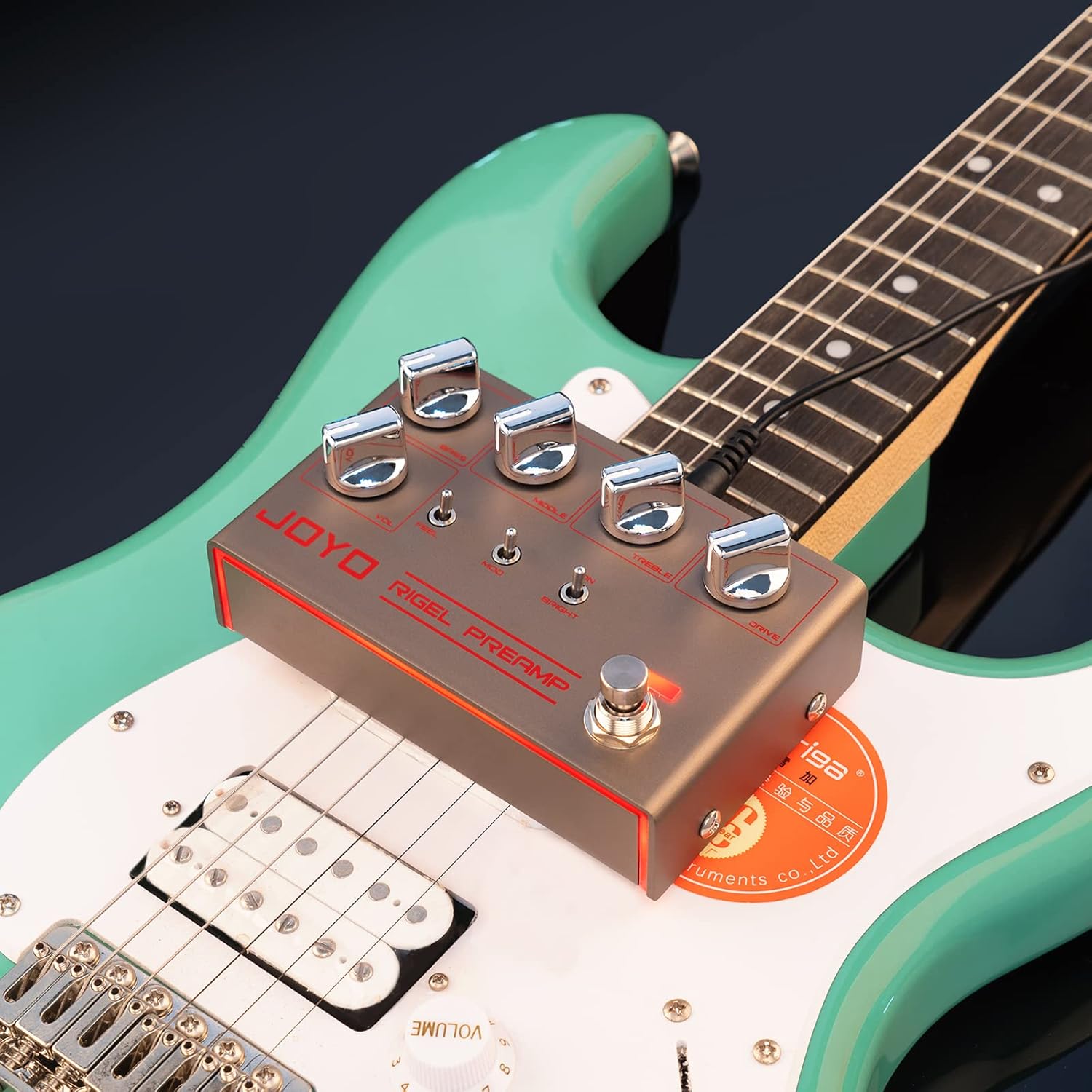 The JOYO Rigel Preamp pedal resting on an electric guitar, showcasing its compact size and design.