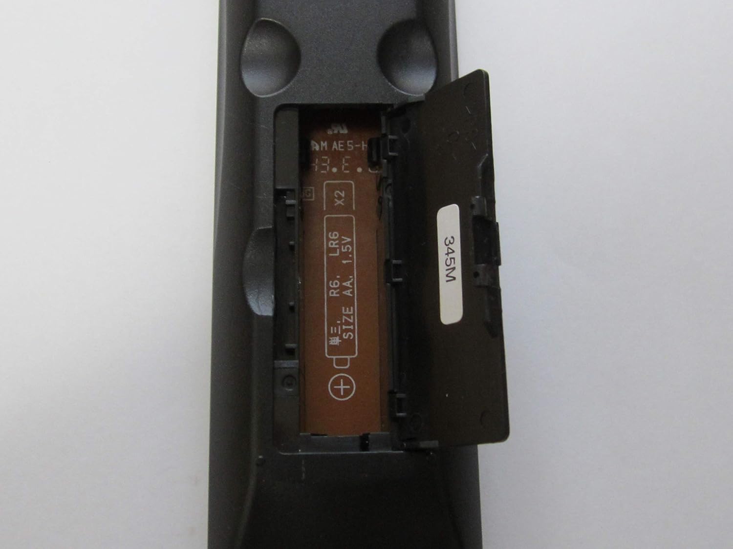 Onkyo RC-487S remote control with the battery compartment open, showing AA battery slots