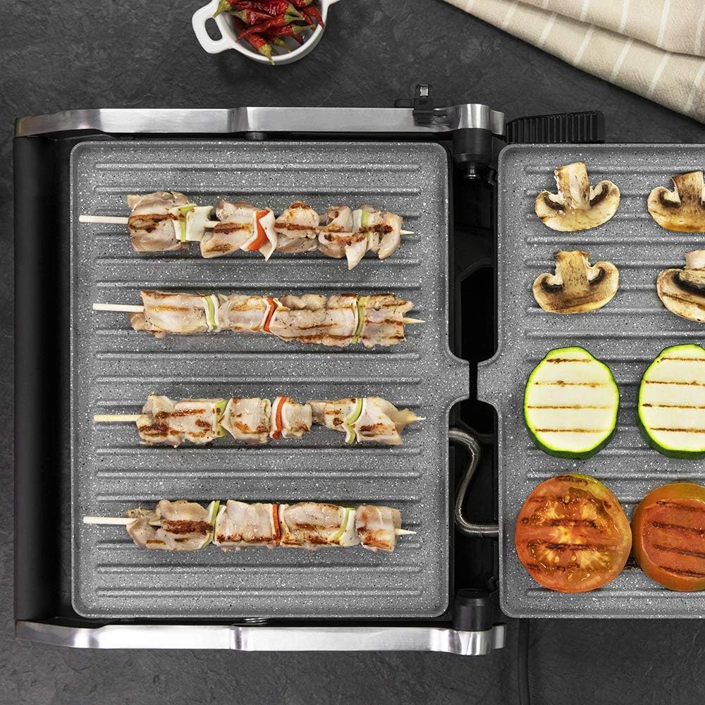Various foods, including chicken skewers, mushrooms, and tomatoes, being grilled on the Cecotec Rock'nGrill 2400 UltraRapid electric grill in its 180-degree open position.