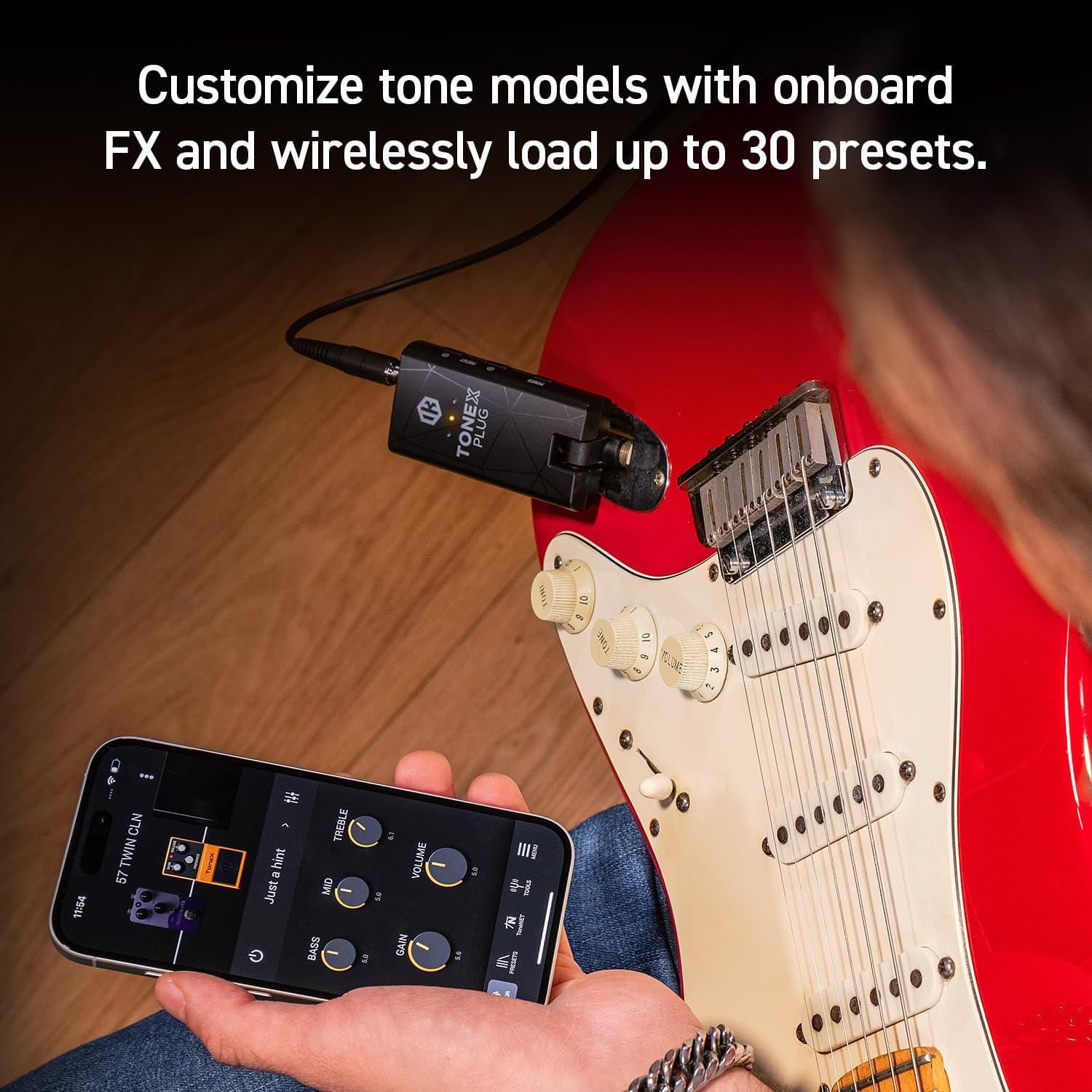 A person using the TONEX Control App on a smartphone while the TONEX Plug is connected to a guitar.
