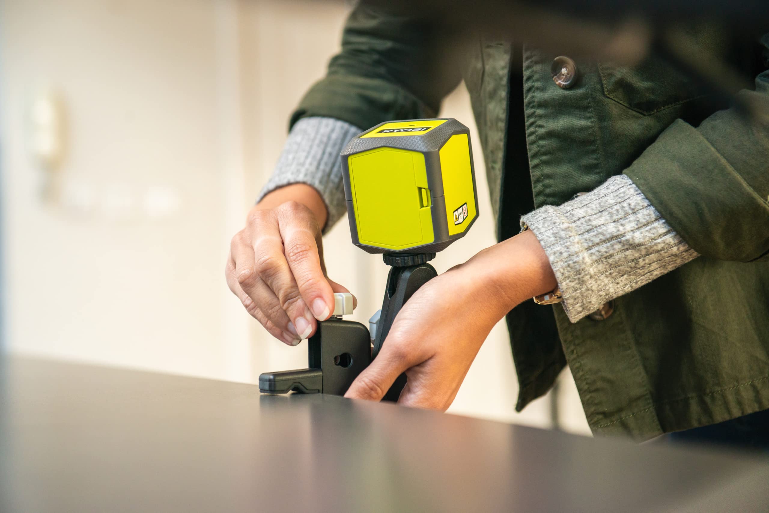 RYOBI - Nivel Láser Verde de 2 líneas en Cruz - Alcance hasta 15 Metros - Tiempo de Nivelación 5 segundos - Compacto y Preciso - 2 Pilas AA, Rosca para Trípode y Pinza de Montaje Incluídas - RBCLLG1