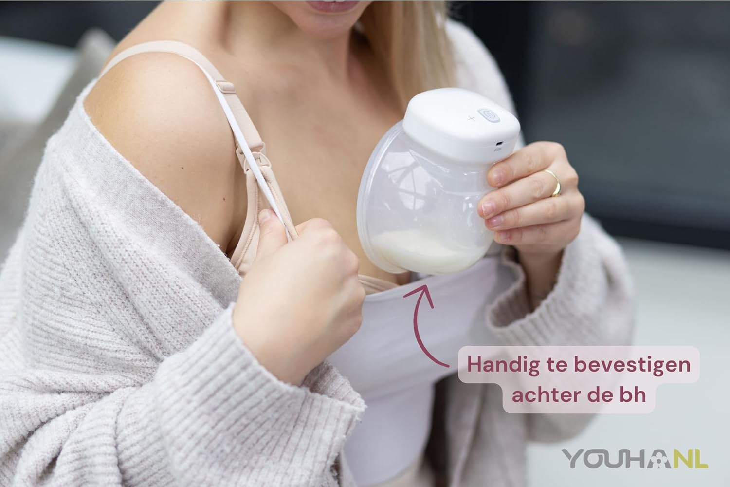 Close-up of a woman attaching the Youha breast pump discreetly behind her bra.