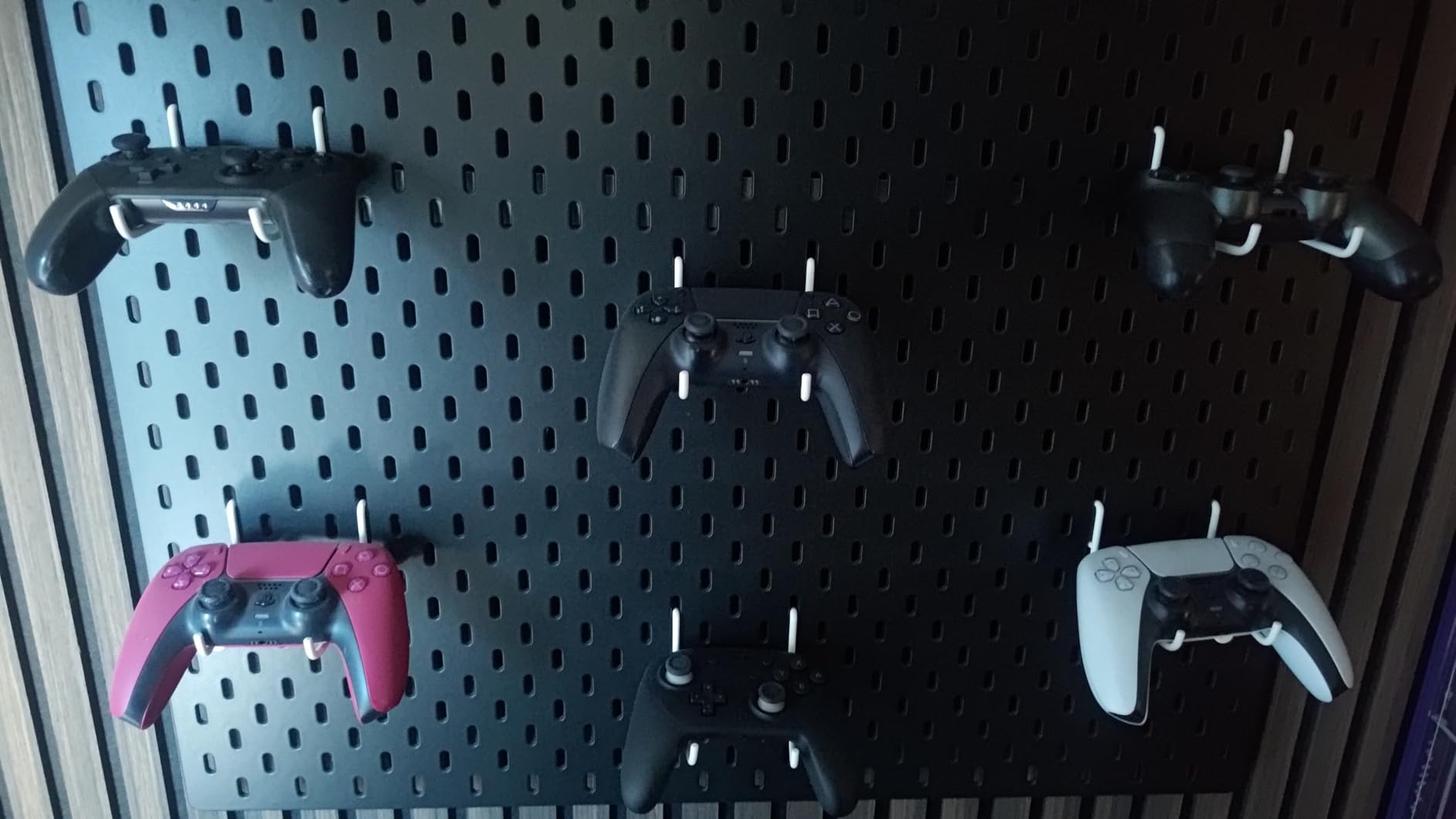 IKEA SKÅDIS hooks holding gaming controllers on a pegboard