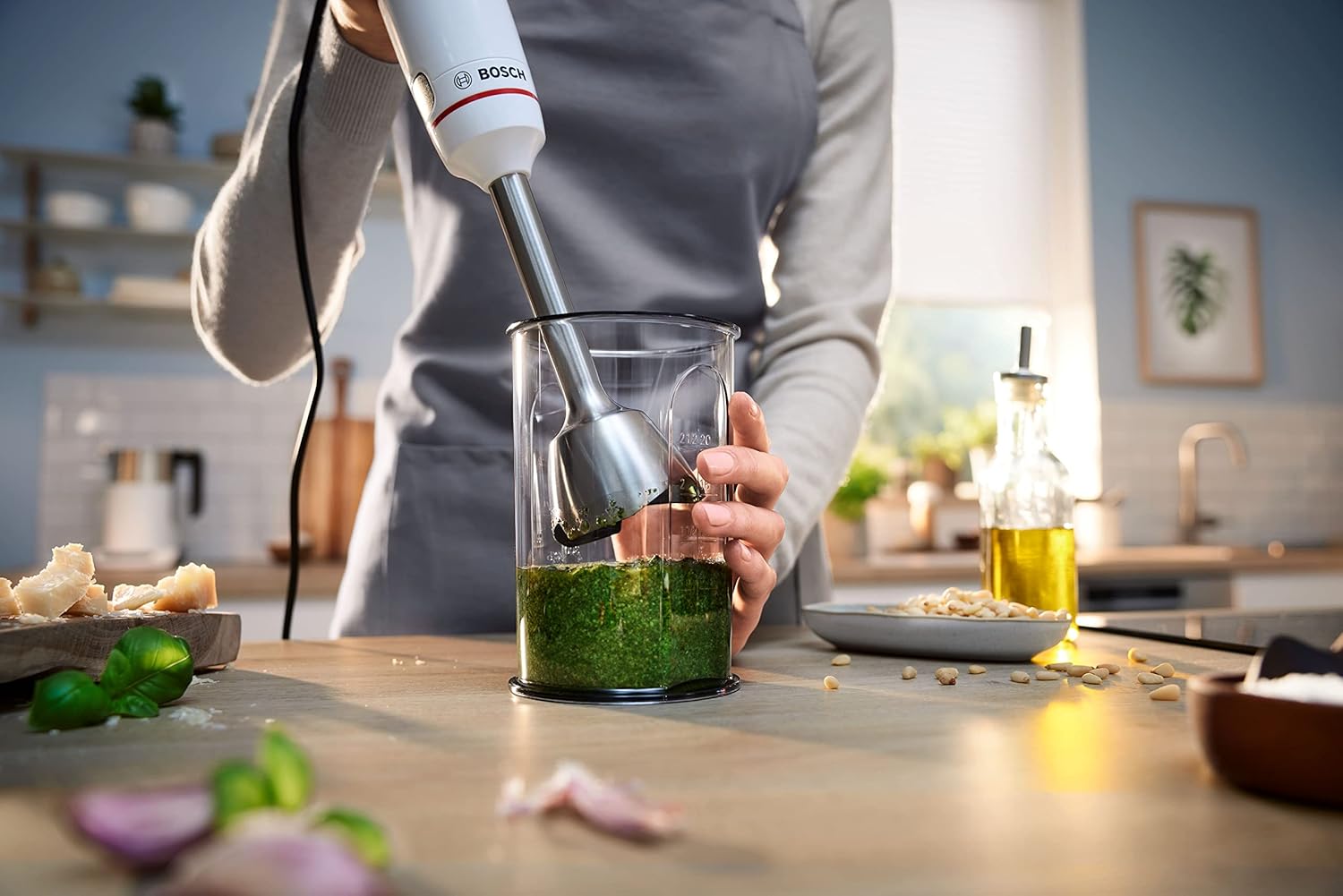 Hand blender mixing pesto in the included mixing beaker