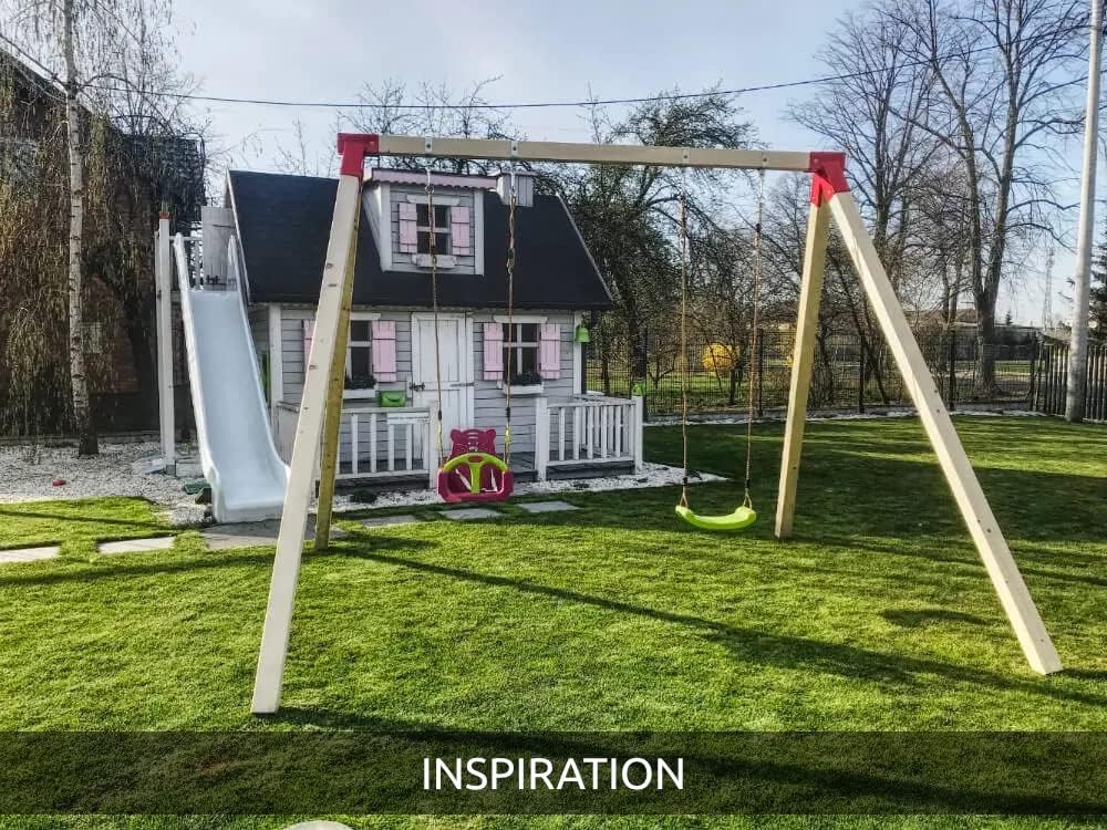 Inspirational image of a fully assembled swing set in a garden next to a playhouse, demonstrating a possible final setup.