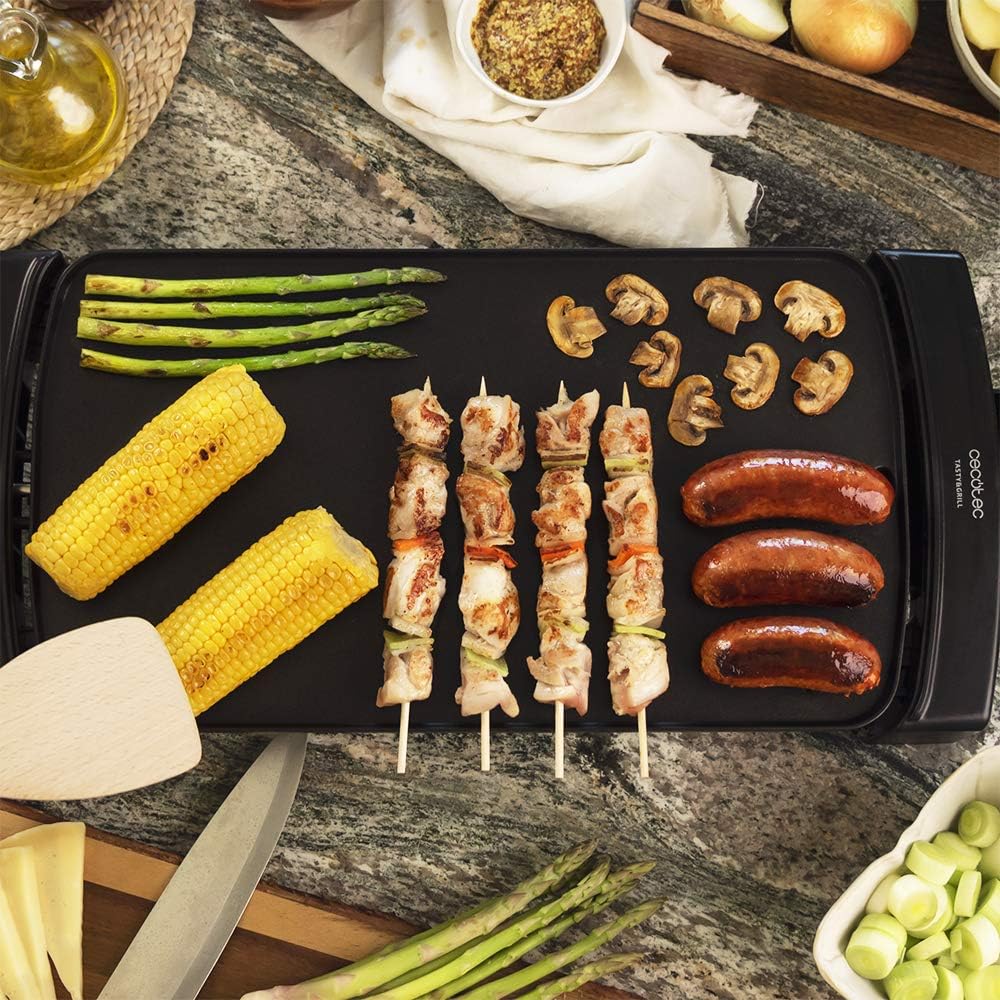 Electric griddle cooking skewers, sausages, corn, asparagus, and mushrooms