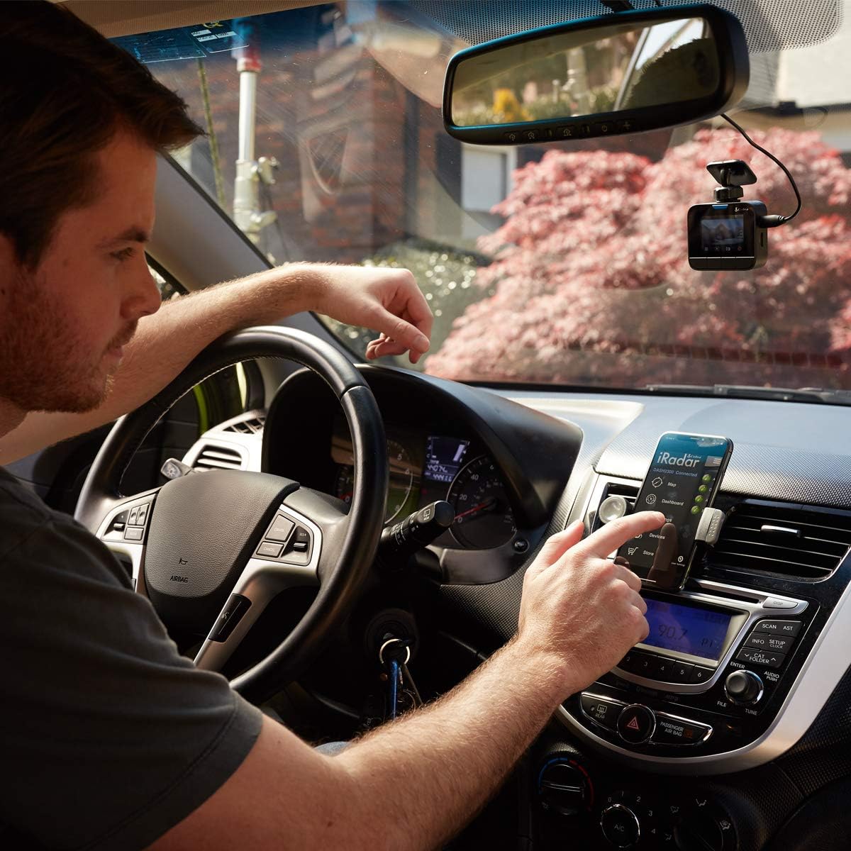 User interacting with the Cobra iRadar app on a smartphone mounted in a car