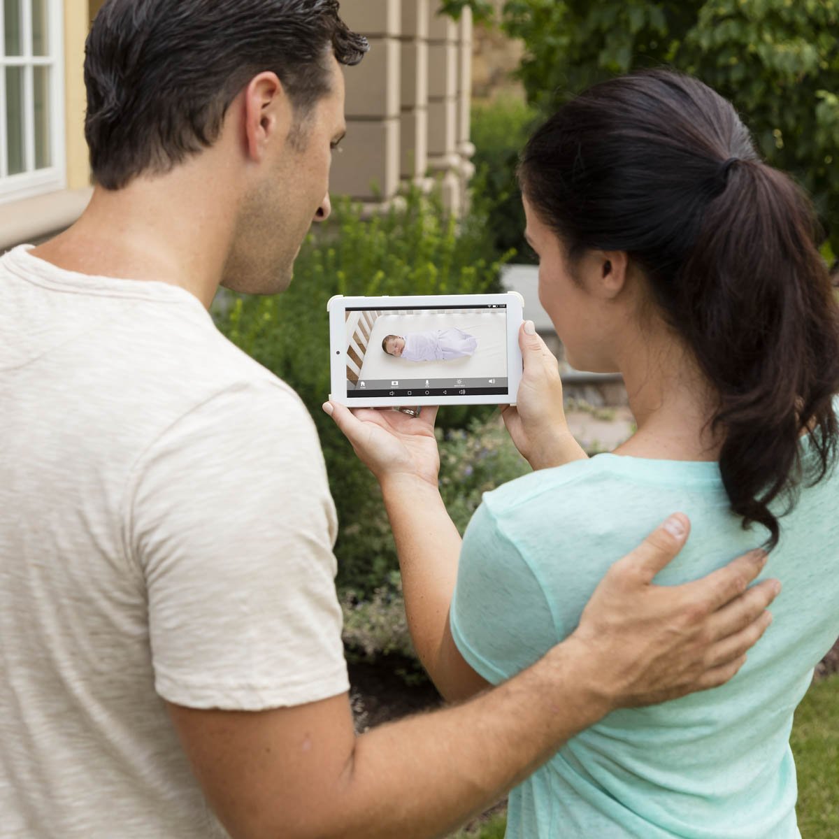 Couple monitoring baby on tablet outdoors