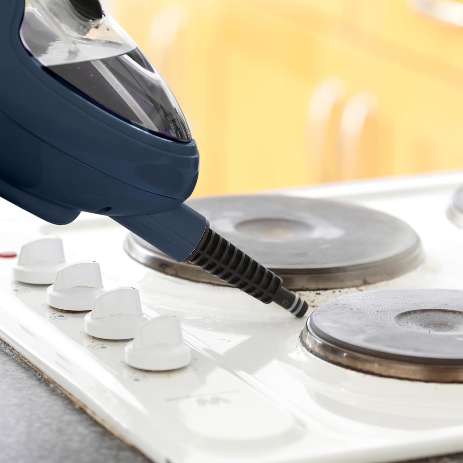 Handheld steam cleaner cleaning a stovetop burner