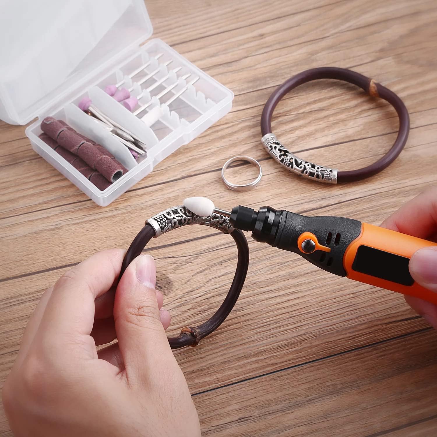 A hand using the rotary tool with a fine bit to engrave or detail a leather bracelet with metal accents.