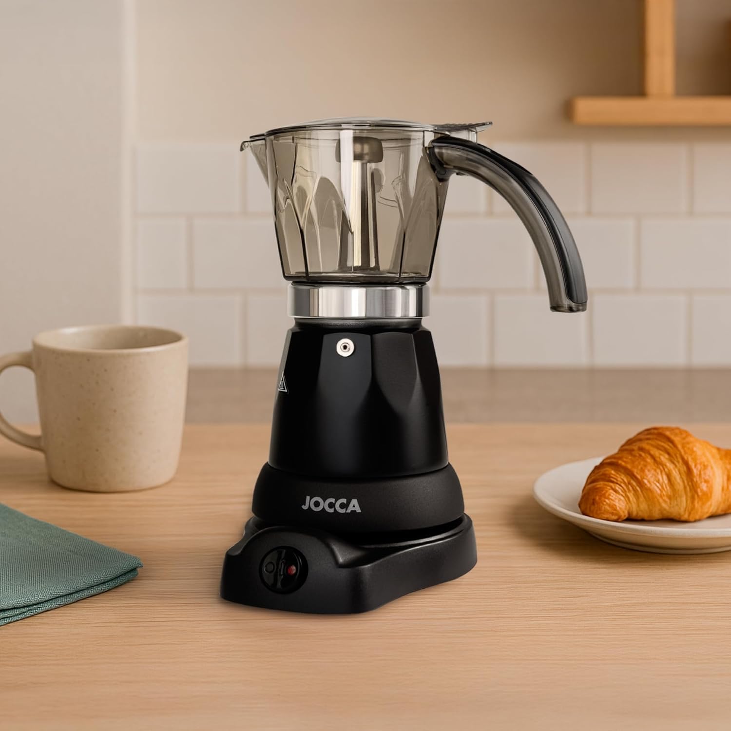 Jocca electric Italian coffee maker assembled on a kitchen counter next to a coffee cup and croissant.