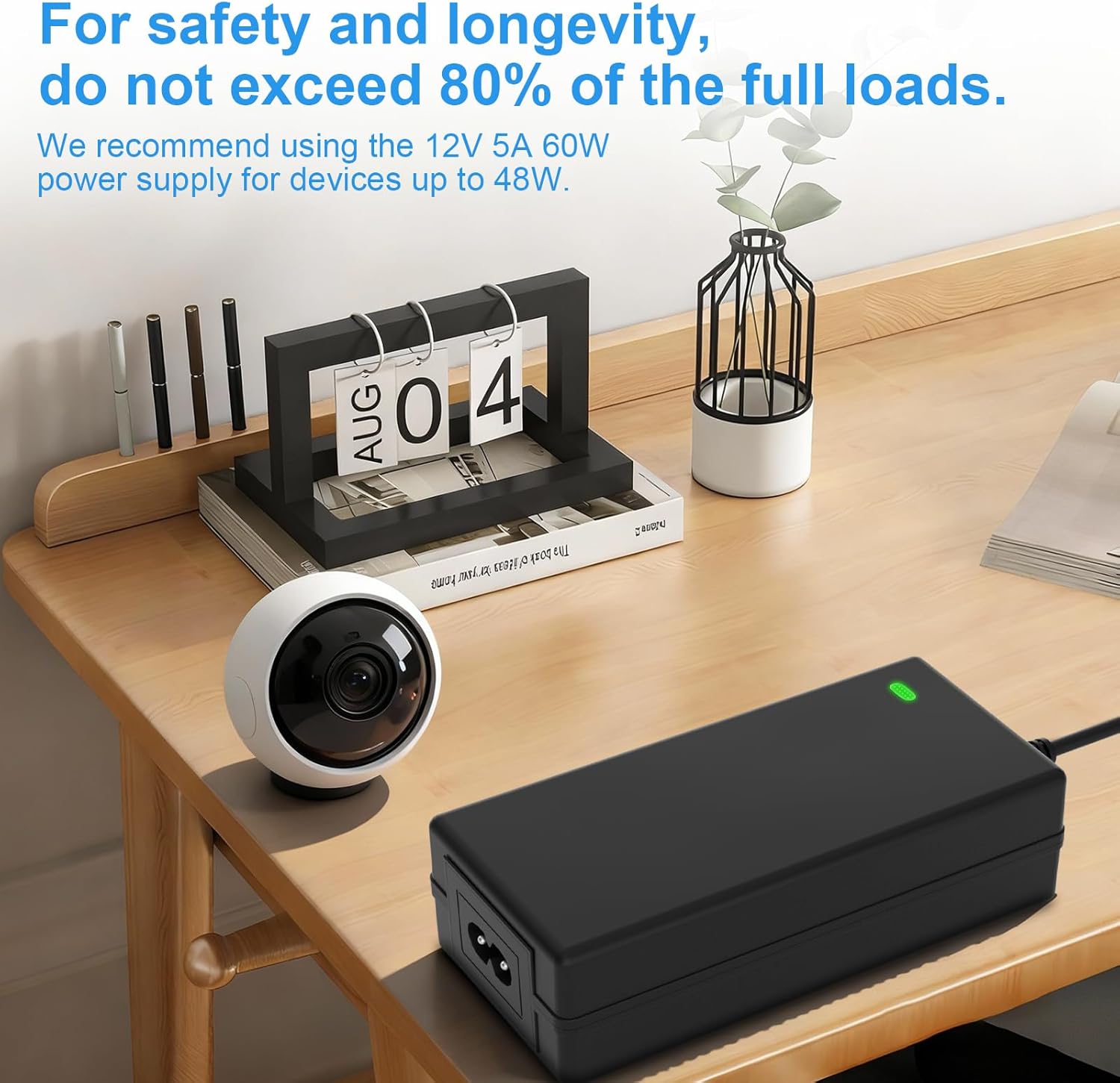 Power supply adapter on a desk with a security camera, illustrating the 80% load recommendation.