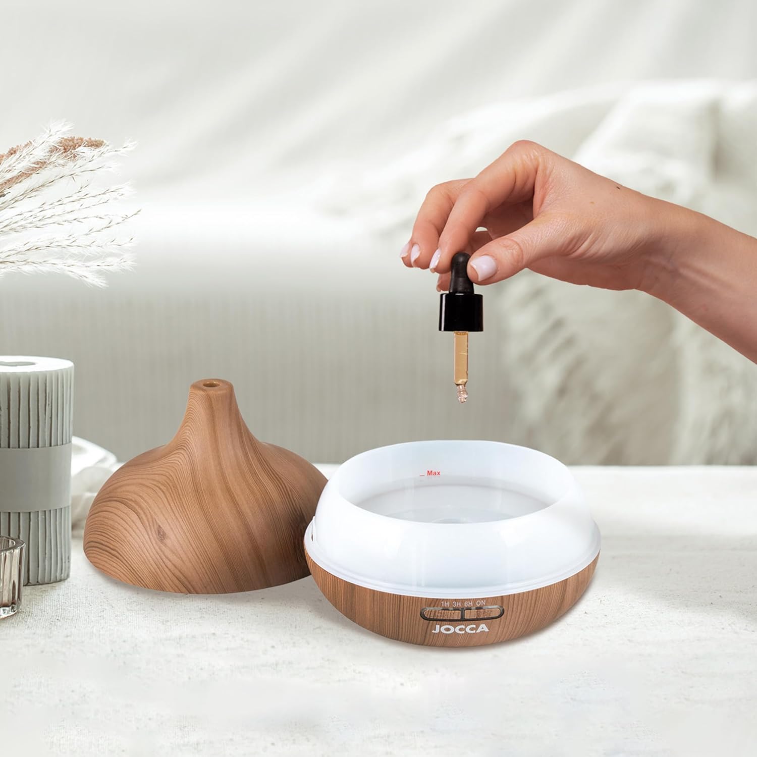 Hand adding essential oil to the diffuser's water tank