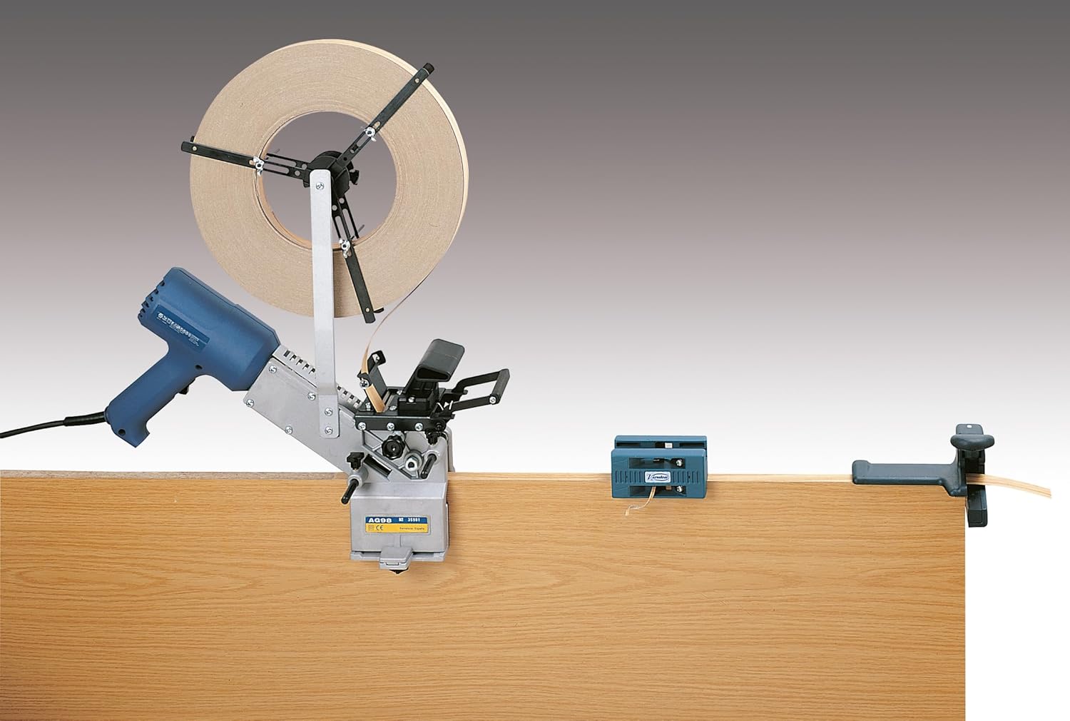 Virutex AG52F Edge Banding Set in operation, showing the applicator, edge banding roll, and trimmer/scraper on a wooden panel.