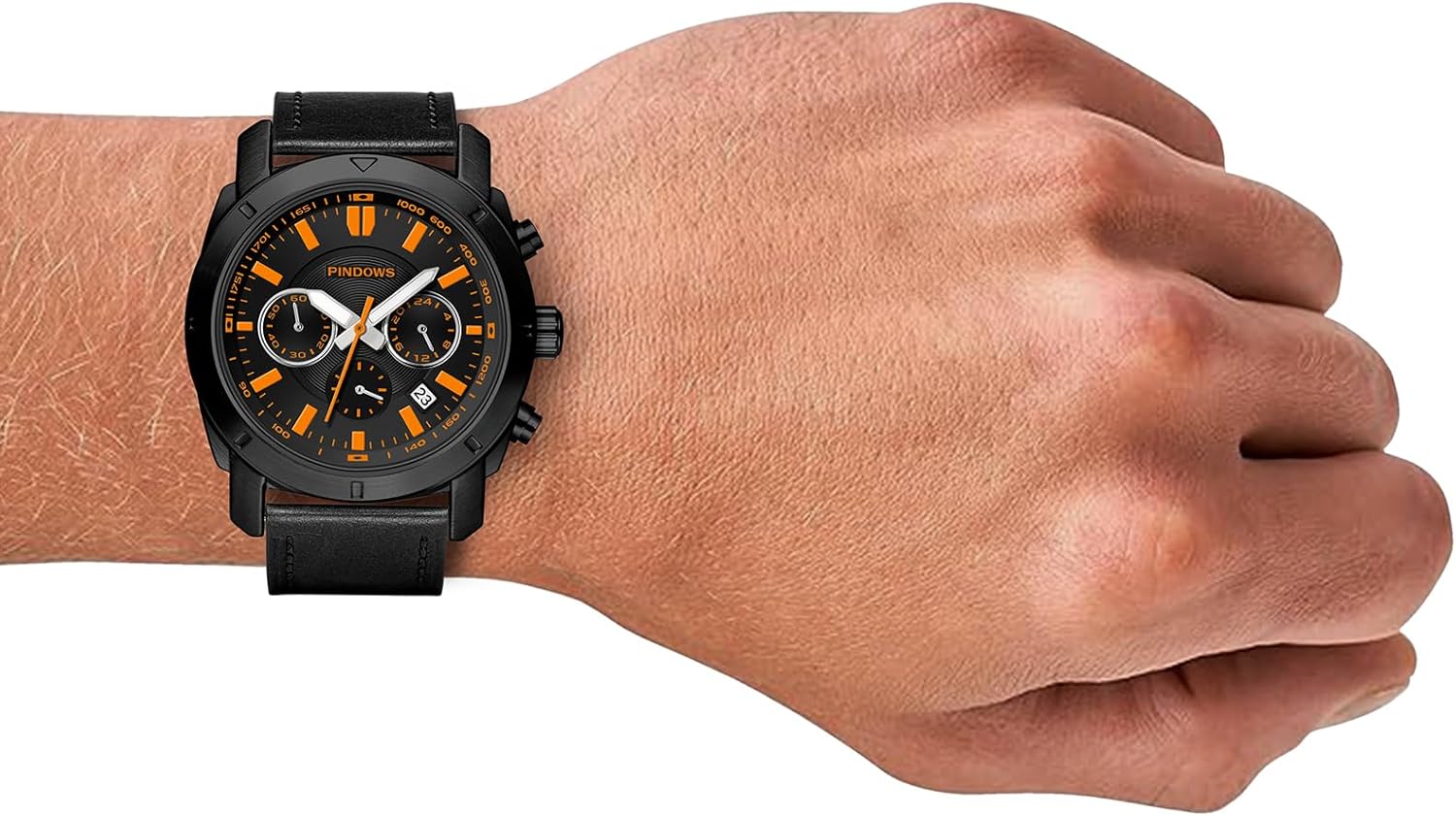 The PINDOWS watch with black case and orange face worn on a wrist.
