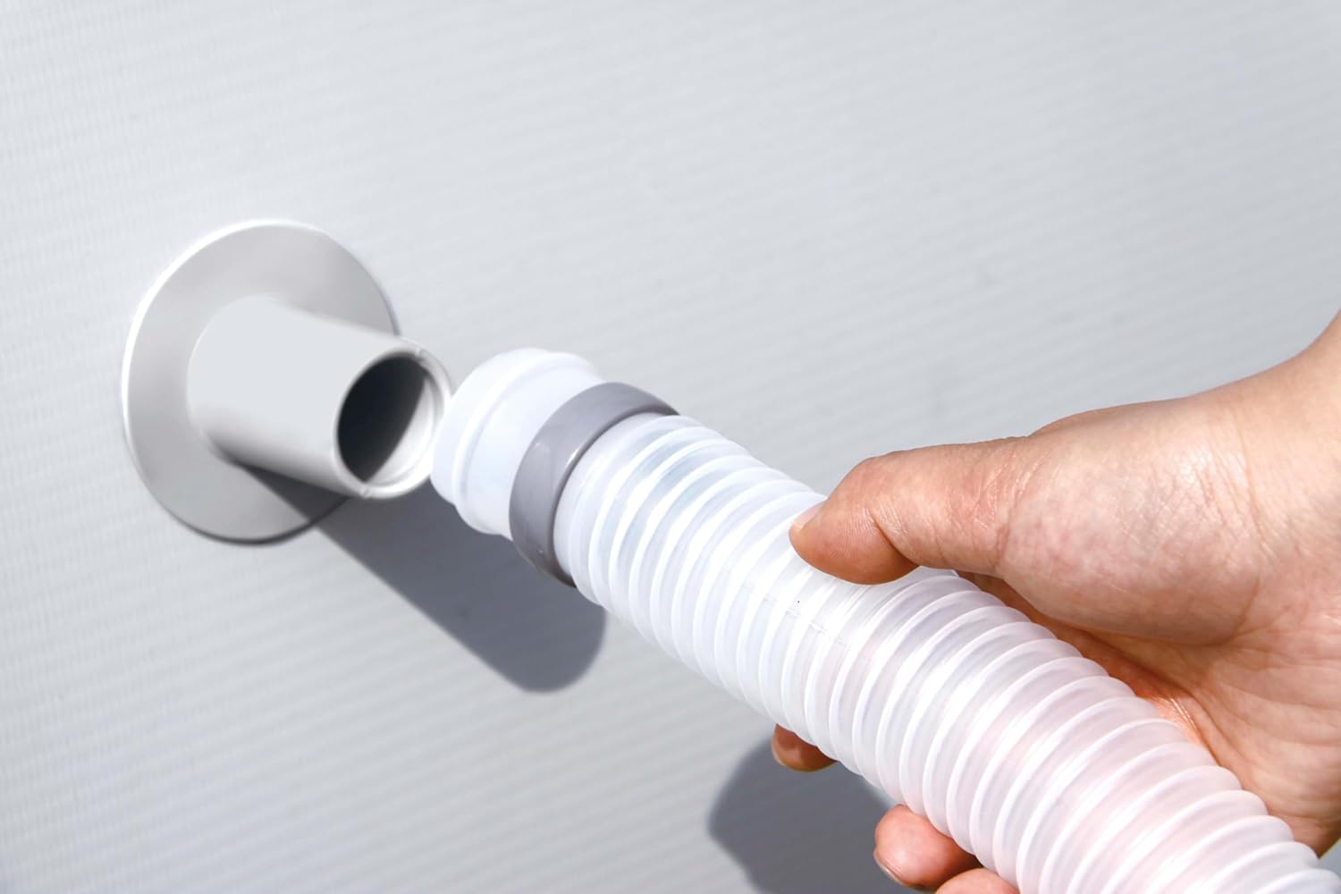 Hand connecting a hose to the pool's return inlet