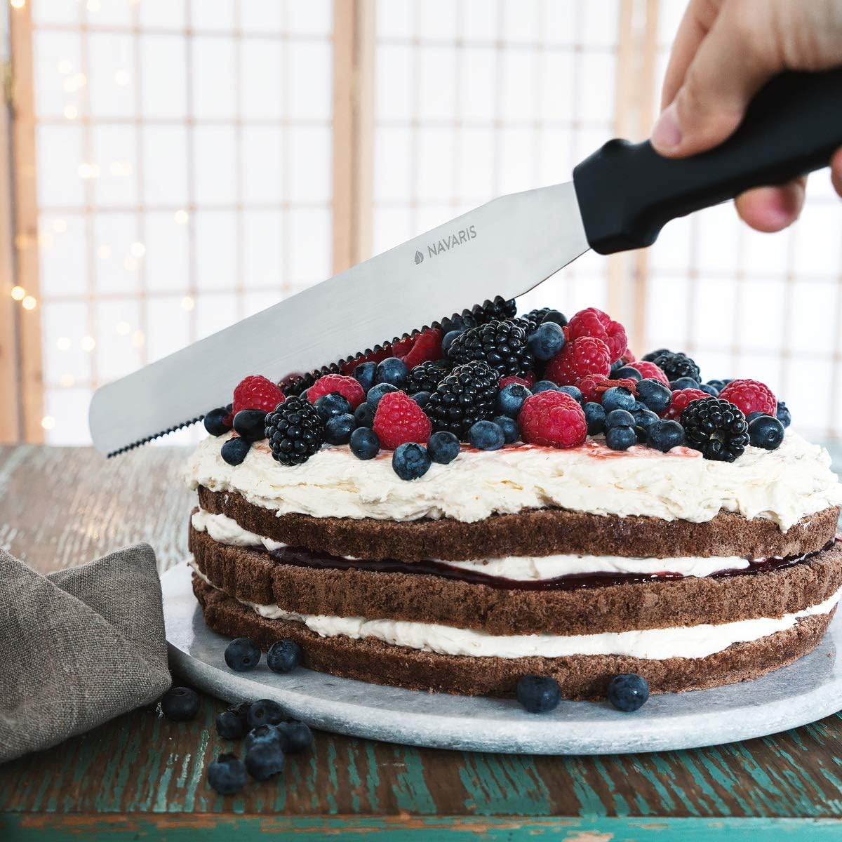 Hand slicing a cake with the serrated knife while the cake is in the ring