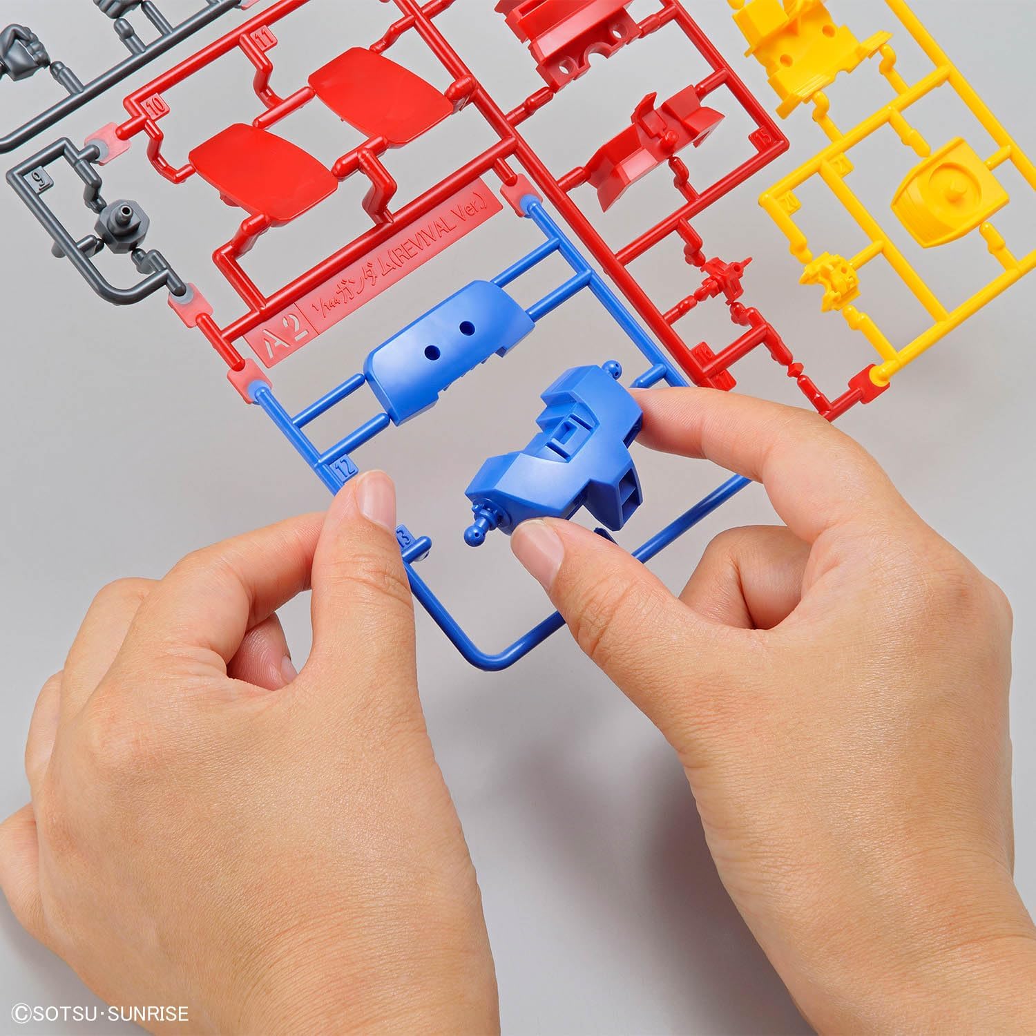Hands assembling a blue part from a plastic runner