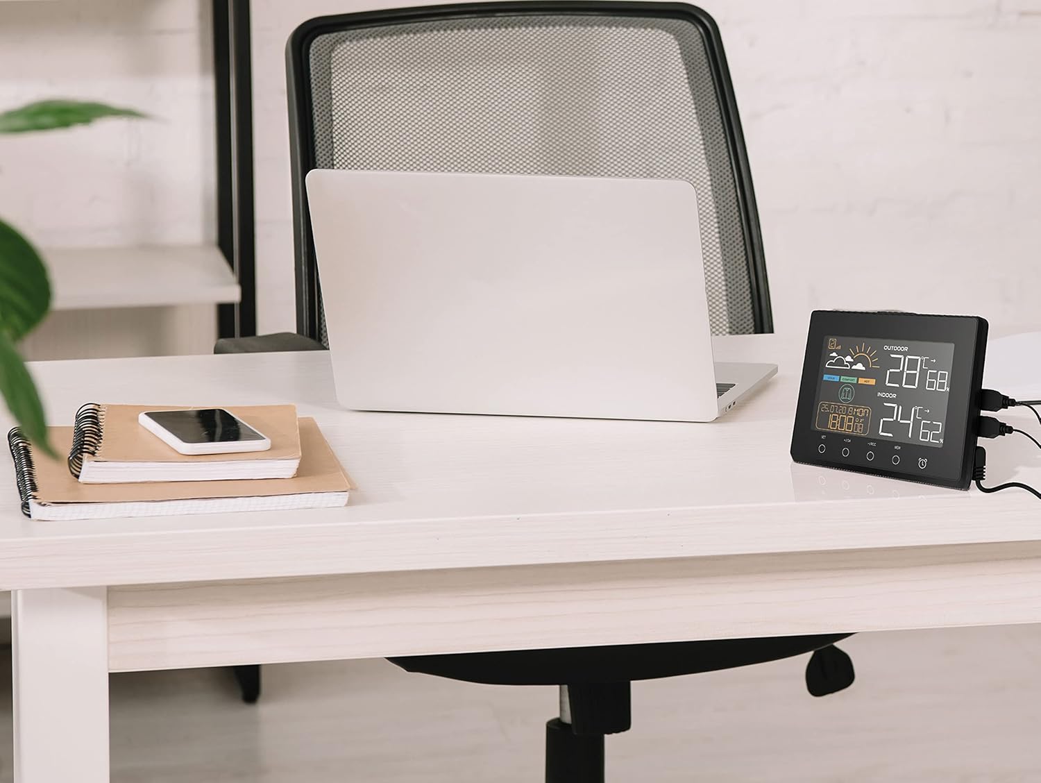 The PUR LINE WS015 Weather Station with two smartphones connected to its USB charging outputs.