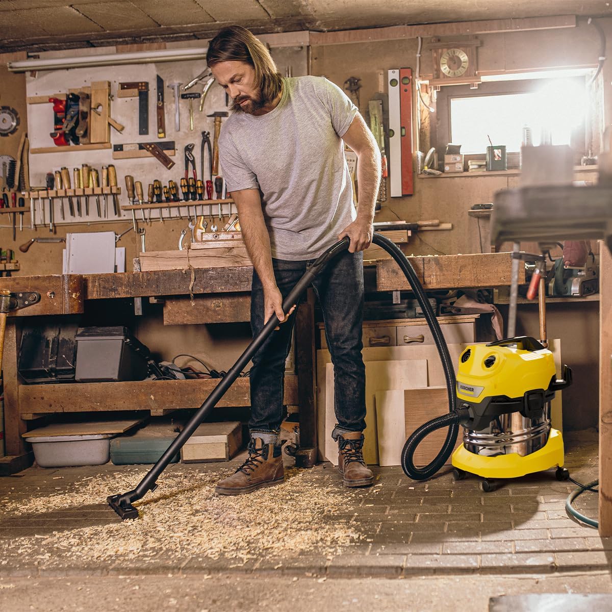 Man dry vacuuming wood chips in a workshop