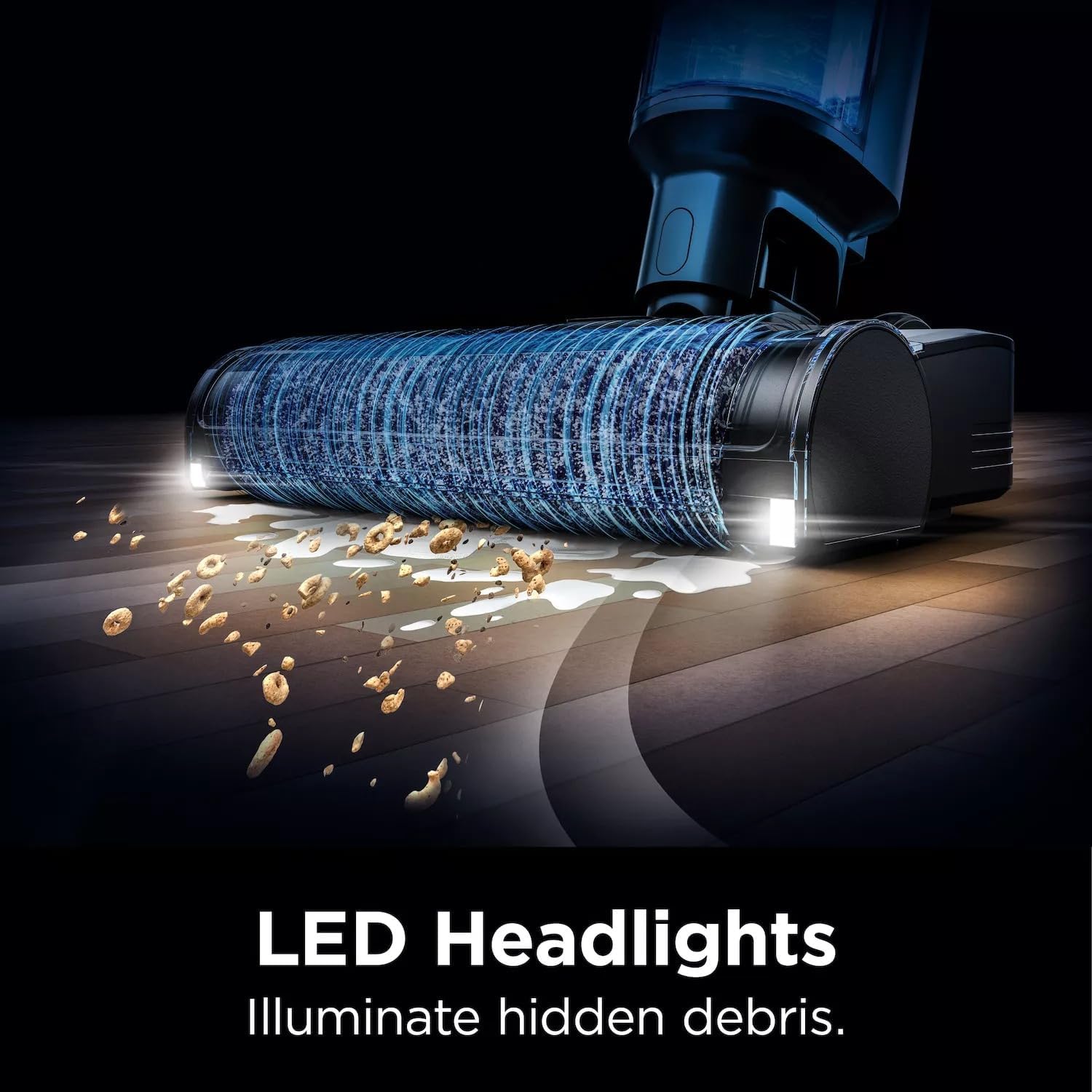 The Shark HydroVac XL's LED headlights illuminating dirt and debris on a floor.