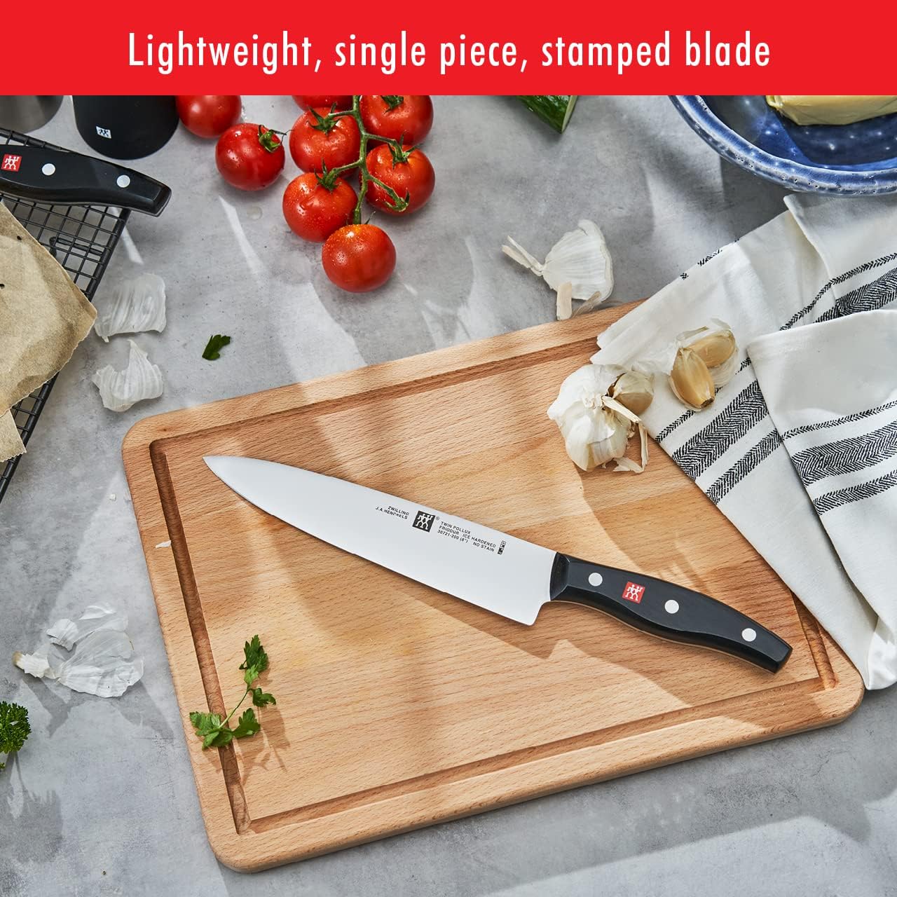 Chef knife on a cutting board with garlic and herbs