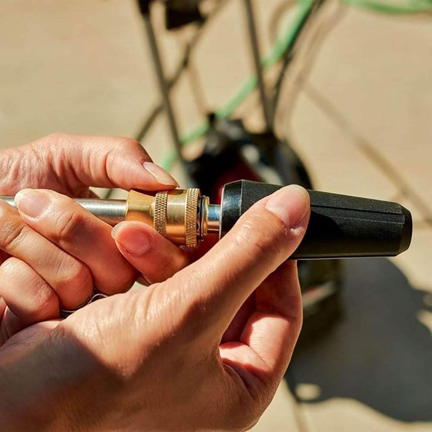 Hands connecting a spray nozzle to the pressure washer wand