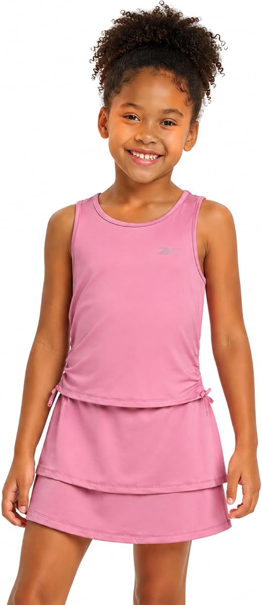 Conjunto de camiseta sin mangas y falda que absorbe la humedad para niñas Reebok, ropa deportiva a juego | Silueta con volantes y pantalones cortos integrados para mayor cobertura, tacto suave y flexible que favorece el juego activo de tenis, baile o práctica.
