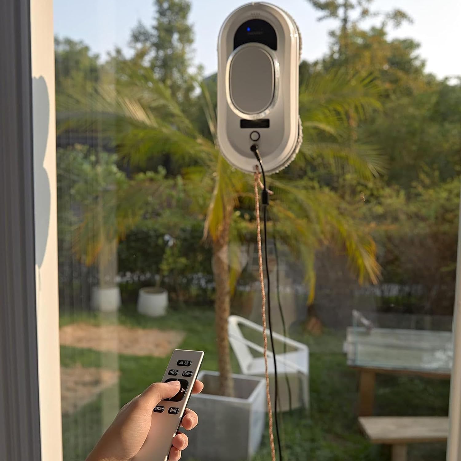 Person using remote control to operate window cleaning robot on a window